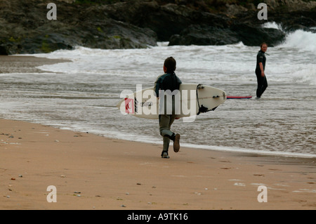 Giovani surfer racing lungo la spiaggia che porta una tavola da surf Foto Stock