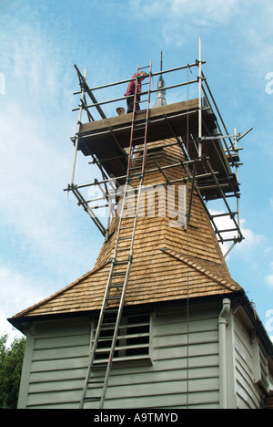 Greensted vicino Ongar St Andrews chiesa parrocchiale torre ponteggio con operai nuova finitura di scandole di copertura del tetto Foto Stock