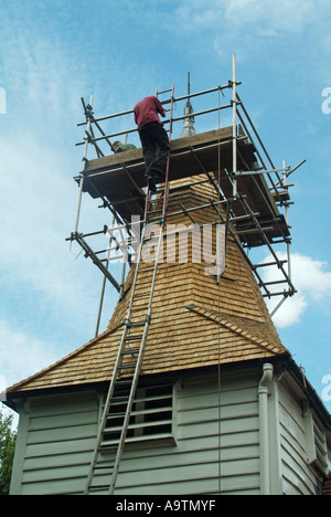 Greensted vicino Ongar St Andrews chiesa parrocchiale torre ponteggio con operai nuova finitura di scandole di copertura del tetto Foto Stock