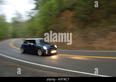 MINI Cooper S guida su un avvolgimento strada rurale al crepuscolo Foto Stock