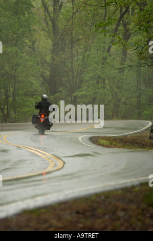 Motocicletta essendo guidato su un molto tortuosa e bagnato strada rurale Foto Stock