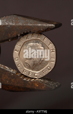 British 20p denaro coin in presa squeeze di pinze a pressione finanziaria nozione Foto Stock