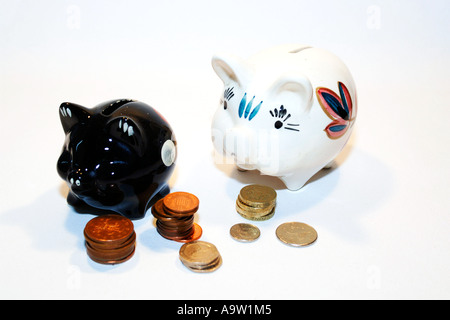 Due macchiato il salvadanaio suini circondato da monete Foto Stock
