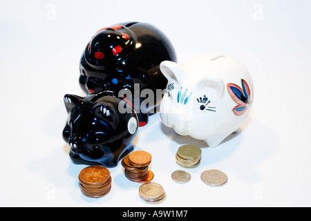 Tre macchiato il salvadanaio suini circondato da monete Foto Stock