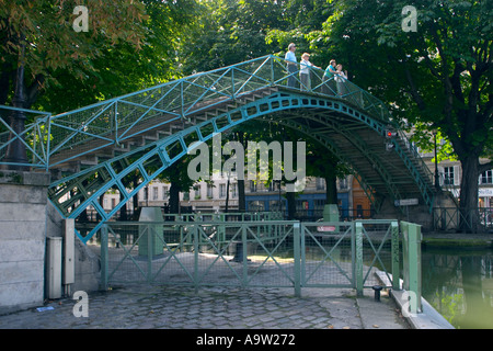 I turisti si godono una passeggiata attraverso la pittoresca Passerelle Bichat, una passerella in metallo che attraversa il Canal Saint-Martin a Parigi, in Francia Foto Stock