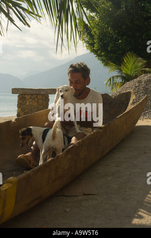 Pescatore seduto con il suo cane in una canoa Picinguaba beach Ubatuba Sao Paulo membro Brasile Foto Stock