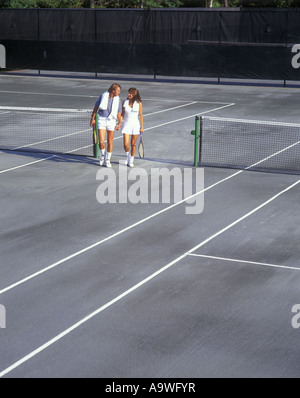 GIOVANE COPPIA CAUCASICA CHE CAMMINA SUL CAMPO DA TENNIS Foto Stock