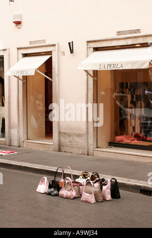 Contraffazione di designer borse in vendita al di fuori del La Perla shop a Roma Italia Foto Stock
