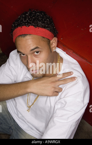 Ritratto di un giovane uomo in hip-hop fashion seduta sul pavimento Foto Stock