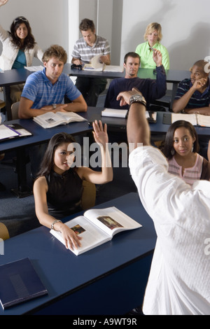 Gli studenti alzando le mani in classe Foto Stock