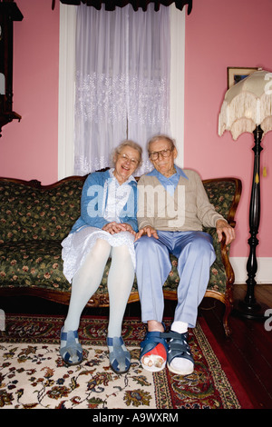 Ritratto di Allegro coppia senior e salotto separato sul divano nel soggiorno Foto Stock