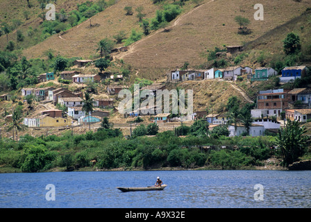 A Cachoeira, Bahia, Brasile. Una vista sul fiume e i poveri area del villaggio e i campi. Un uomo pesca dal suo canoa. Foto Stock