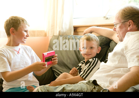 Una bionda uomo con i suoi due figli seduti su un lettino a casa Foto Stock