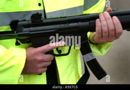 Un funzionario di polizia in un giubbotto riflettenti tenendo un Heckler e Koch MP5 mitragliatrice Foto Stock