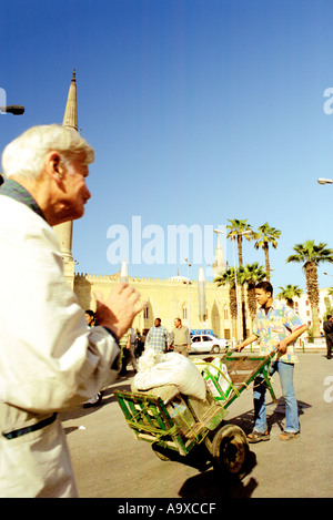 Persone che passano il Sayyidna al Hussein moschea nella vecchia parte islamica del Cairo in Egitto Foto Stock