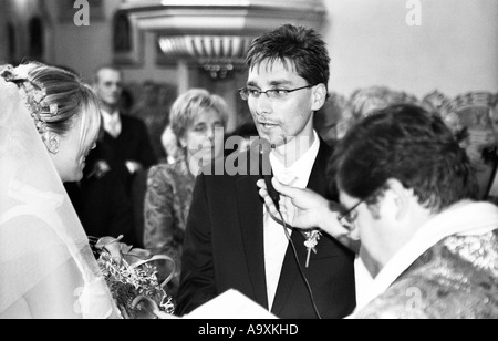 La Polonia, a Lodz, sposa e lo sposo lo scambio di voti nella parte anteriore del sacerdote nella chiesa (B&W) Foto Stock