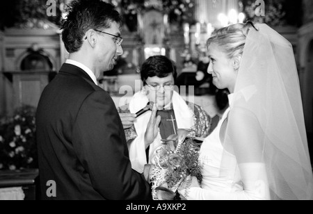 La Polonia, a Lodz, sposa e lo sposo lo scambio di voti nella parte anteriore del sacerdote nella chiesa (B&W) Foto Stock