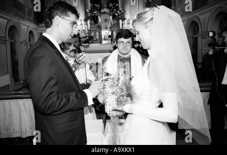 La Polonia, a Lodz, sposa e lo sposo lo scambio di voti nella parte anteriore del sacerdote nella chiesa (B&W) Foto Stock