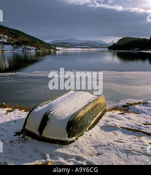 Una barca capovolta coperto di neve fresca attende il suo tempo fino a primavera prossima al bordo del Loch Pityoulish, Cairngorm, Scozia. Foto Stock