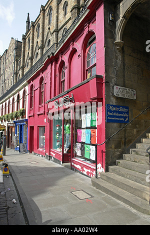 Una vista lungo il Victoria Street nella Città Vecchia di Edimburgo con negozi colorati e una stretta che conduce al Castello di Edinburgo Foto Stock