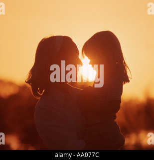 Azienda madre figlia piccola in armi al tramonto Foto Stock