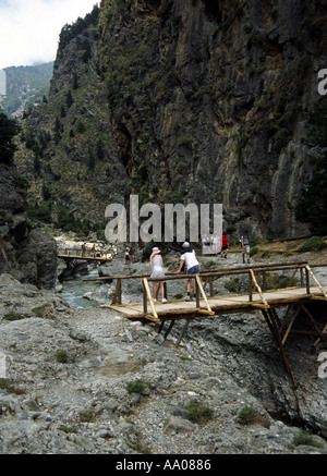 Escursionisti che attraversano due ponti di legno sul fiume alla fine del sentiero roccioso nella gola di Samaria, Creta Foto Stock