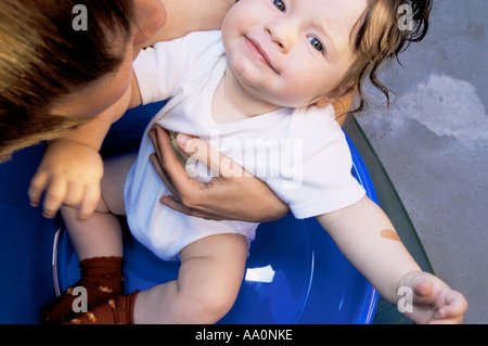 La Polonia, madre assistere bambina (6-9 mesi) seduti nella vasca di lavaggio, ritratto Foto Stock