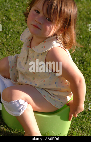 Bambino seduto su un vasino all'aperto nel giardino Foto Stock