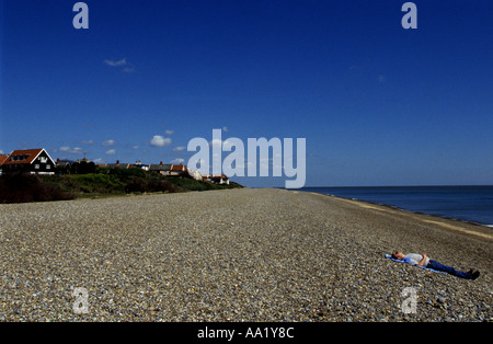 L uomo a prendere il sole sulla spiaggia a Thorpeness vicino a Aldeburgh, Suffolk, Regno Unito. Foto Stock