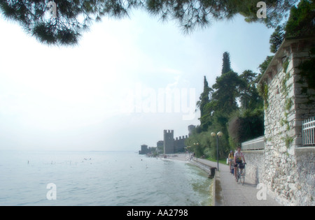 Soft focus shot di ciclisti sulla riva del lago il percorso attorno alla città vecchia, a Sirmione sul Lago di Garda, Italia Foto Stock