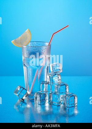Bicchiere di acqua minerale con cubetti di ghiaccio e limone con cannuccia Foto Stock