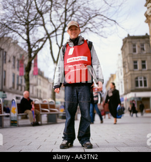 L'operaio benefico sorridente giovane uomo chugger cantare a Queen Street a Cardiff per le donazioni benefiche di aiuti in Gran Bretagna KATHY DEWITT Foto Stock