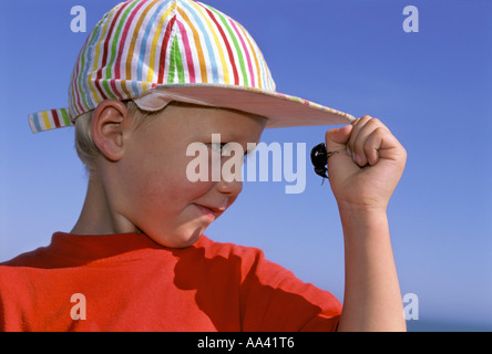Little Boy quattro anni guardando un coleottero nero sulla sua mano Foto Stock