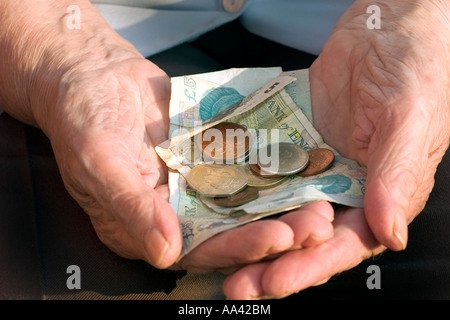 Anziani womans mano azienda british monete banconote Foto Stock