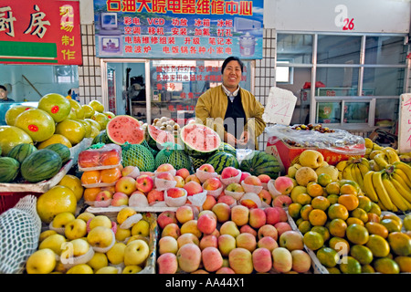 Cina Pechino sorridente fornitore con una ampia varietà di frutta fresca per la vendita nel mercato di vicinato a Pechino Foto Stock