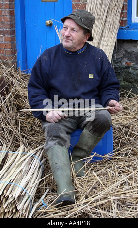 La Thatcher lavorando sul tetto di paglia del villaggio di Adare County Limerick Irlanda Foto Stock