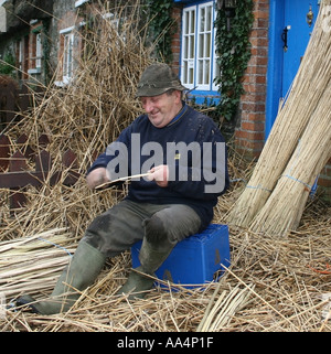 La Thatcher lavorando sul tetto di paglia del villaggio di Adare County Limerick Irlanda Foto Stock