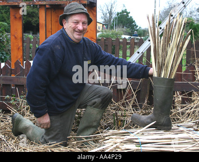 La Thatcher lavorando sul tetto di paglia del villaggio di Adare County Limerick Irlanda Foto Stock