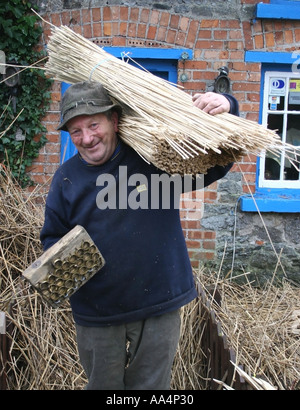 La Thatcher lavorando sul tetto di paglia del villaggio di Adare County Limerick Irlanda Foto Stock