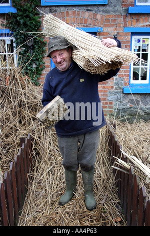 La Thatcher lavorando sul tetto di paglia del villaggio di Adare County Limerick Irlanda Foto Stock