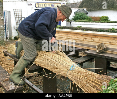 La Thatcher lavorando sul tetto di paglia del villaggio di Adare County Limerick Irlanda Foto Stock