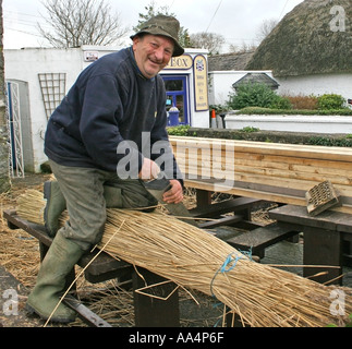 La Thatcher lavorando sul tetto di paglia del villaggio di Adare County Limerick Irlanda Foto Stock