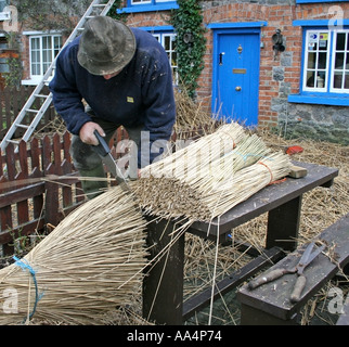 La Thatcher lavorando sul tetto di paglia del villaggio di Adare County Limerick Irlanda Foto Stock