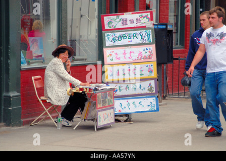 Donna vendita dipinti Cinesi in Chinatown in NYC. Foto Stock