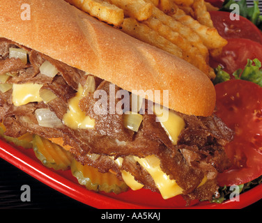 Close up di Philly stile di Philadelphia cheese steak sandwich fritto francese frigge il pomodoro tomatoe roll bun cipolle targhetta rossa le carni bovine in salamoia Foto Stock