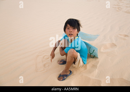 Mui Ne, Vietnam. Ragazzo giovane azienda slitta di sabbia disegno in sabbia a dune di sabbia bianca Foto Stock