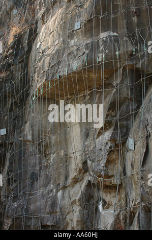 I fili d'acciaio inchiodati nelle rocce per evitare frane sulla ferrovia di Konkan in India Foto Stock