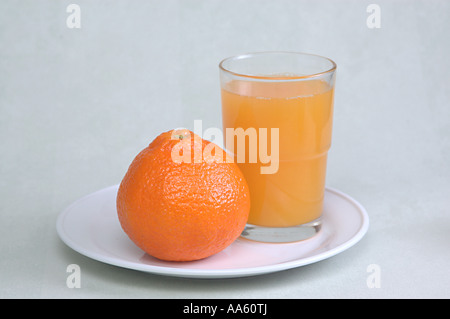 Frutta di arancia in piatto e succo d'arancia in bicchiere Foto Stock