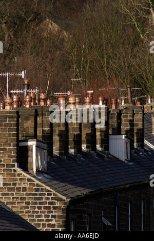 Camini e comignoli sui tetti dei tipici terrazzamenti a nord sulla collina in Bingley Foto Stock