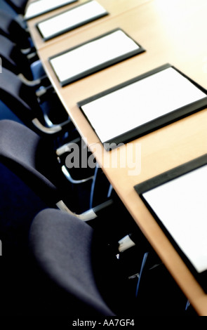 Sedie nere e blotter pad in pelle su un lungo tavolo in legno in una sala riunioni vuota Foto Stock